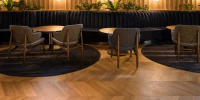 Light golden-brown wood flooring in a chevron pattern in a lounge area.